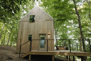A wooden cabin with a single door and window, surrounded by trees. - Where the Woods Meets the Pasture/Private/Hot Tub (Logan)