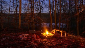 Un feu de camp dans une forêt, avec des bancs et une table à proximité.