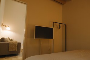 Ein Schlafzimmer mit Bett, Wandfernseher, Nachttisch und Lampe.