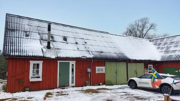 Un bâtiment en bois rouge, avec un toit recouvert de neige, et une voiture blanche garée devant.