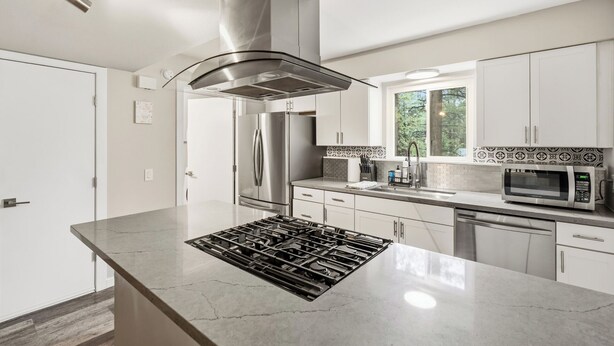 Een moderne keuken met een centraal eiland, roestvrijstalen apparatuur en een raam met uitzicht op de omgeving.