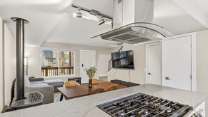Een moderne keuken met een centraal eiland, een ingebouwde kookplaat en een eethoek met een tafel en stoelen.