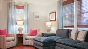 Una sala de estar con sillones a rayas, un sofá azul y dos lámparas.