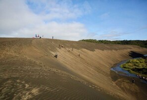 A large, barren hill with a small group of people scattered across it.