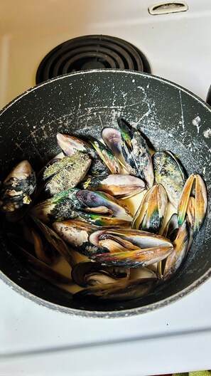 A pot containing mussels on a stove.