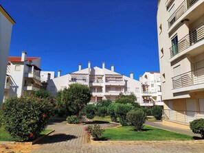 A residential building with multiple balconies, a paved courtyard, and surrounding greenery. - Falésia Beach Apartment by Be Cherish (Albufeira)