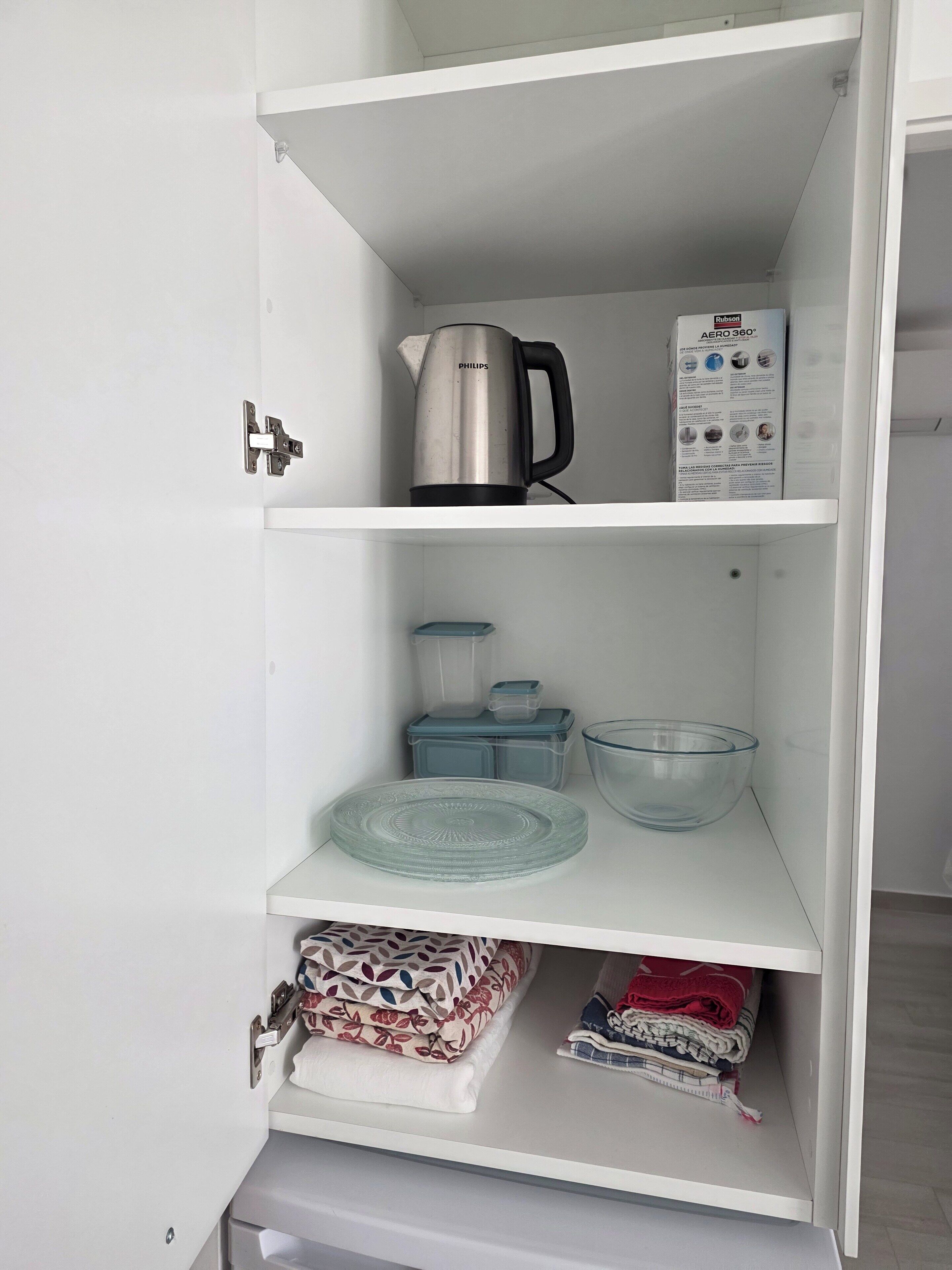 A white cabinet with a kettle, a box of Rubizon Aero 360, and storage containers.