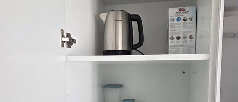 A white cabinet with a kettle, a box of Rubizon Aero 360, and storage containers.