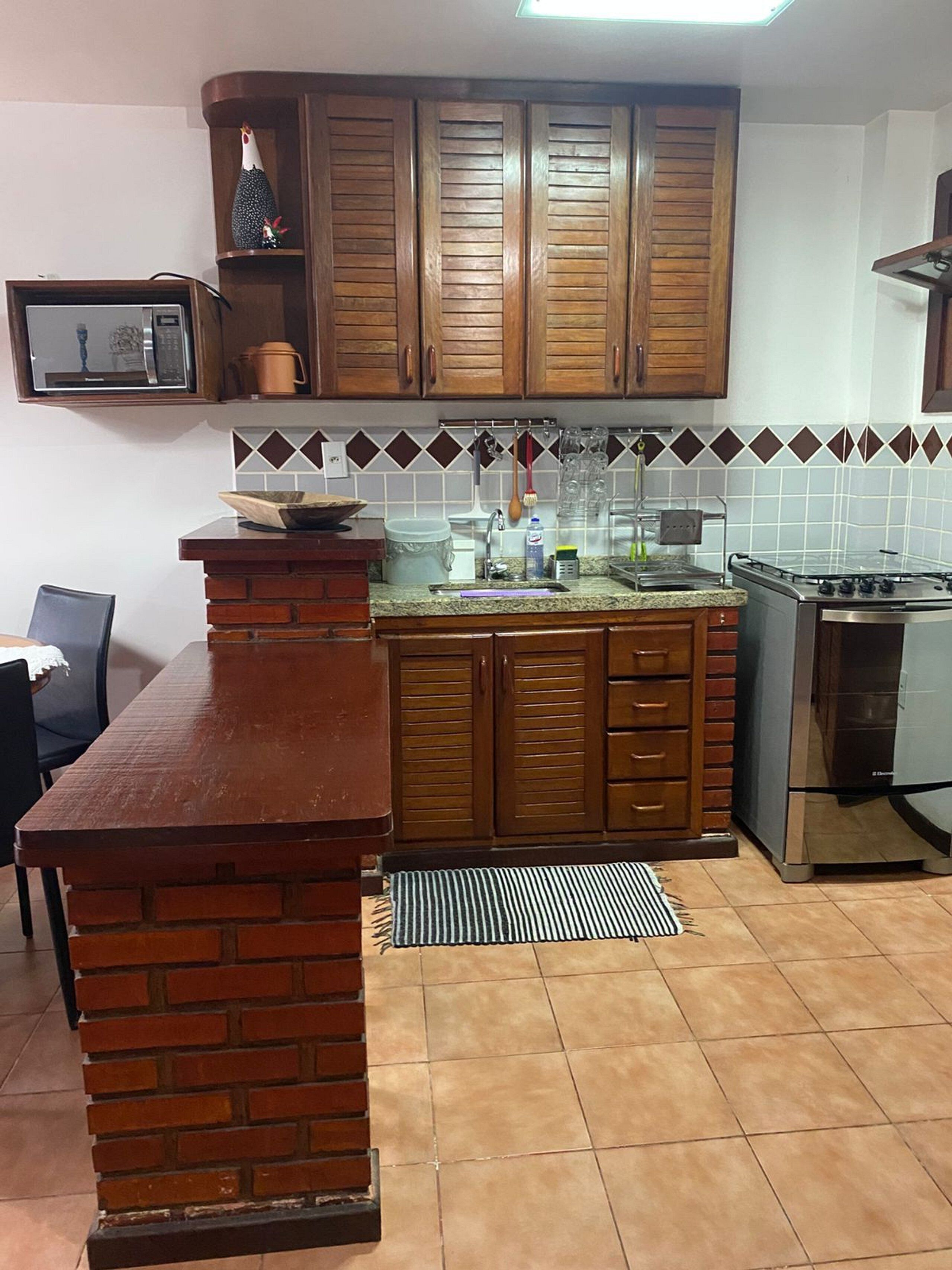 A kitchen with wooden cabinets, a microwave, a stove, and a tiled backsplash.