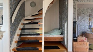 Una stanza compatta con un letto a castello, un piccolo specchio tondo e una scala in legno.