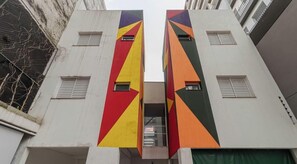 Ein Gebäude mit zwei vertikalen Teilen, wobei jeder Teil ein geometrisches Muster in Rot, Gelb und Grün aufweist.