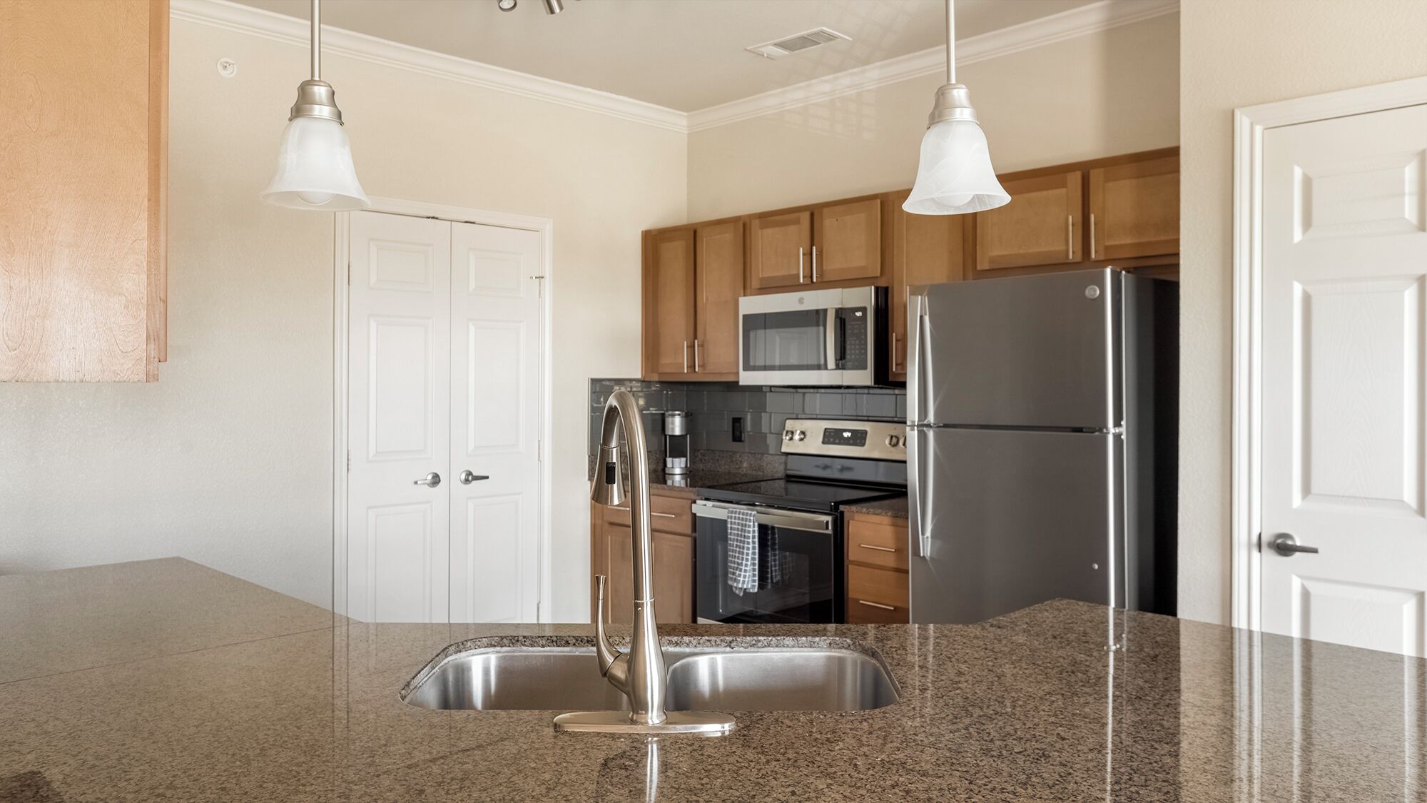 A modern kitchen with granite countertops, stainless steel appliances, and wooden cabinets.
