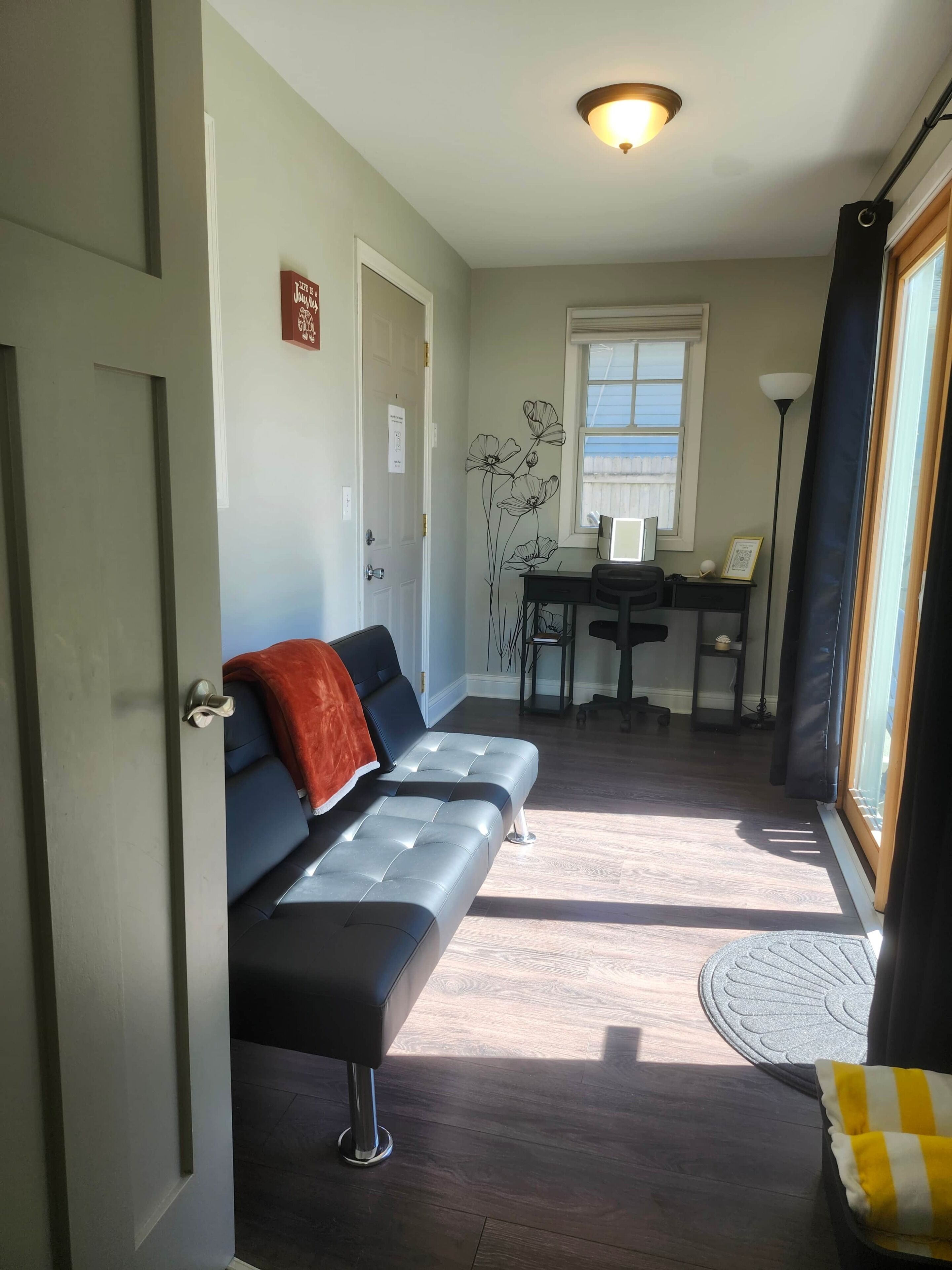 Ein Zimmer mit einer Couch, einem Schreibtisch, einem Stuhl und einem Fenster.