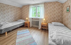 A room with two single beds, a radiator, a window with curtains, and a patterned rug. - Cozy home in årjäng with WiFi (Årjäng)