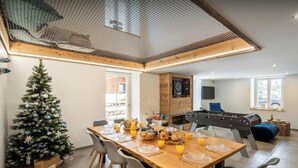 Un coin repas avec une table en bois mise pour le petit-déjeuner, un sapin de Noël et une table de baby-foot.