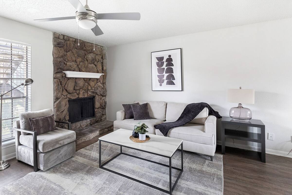 A modern living room with a stone accent wall, a fireplace, a sofa, a coffee table, and a floor lamp.