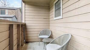 A small, enclosed porch area with two wicker chairs and a small table. - Landing Apartments near Southridge (Denton)