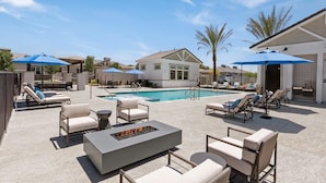 Un espace aménagé au bord de la piscine, avec des chaises longues, des parasols et un foyer.
