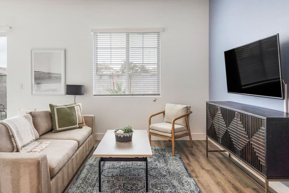 Una sala de estar moderna con un sofá, una mesa de centro, un televisor y un mueble aparador.