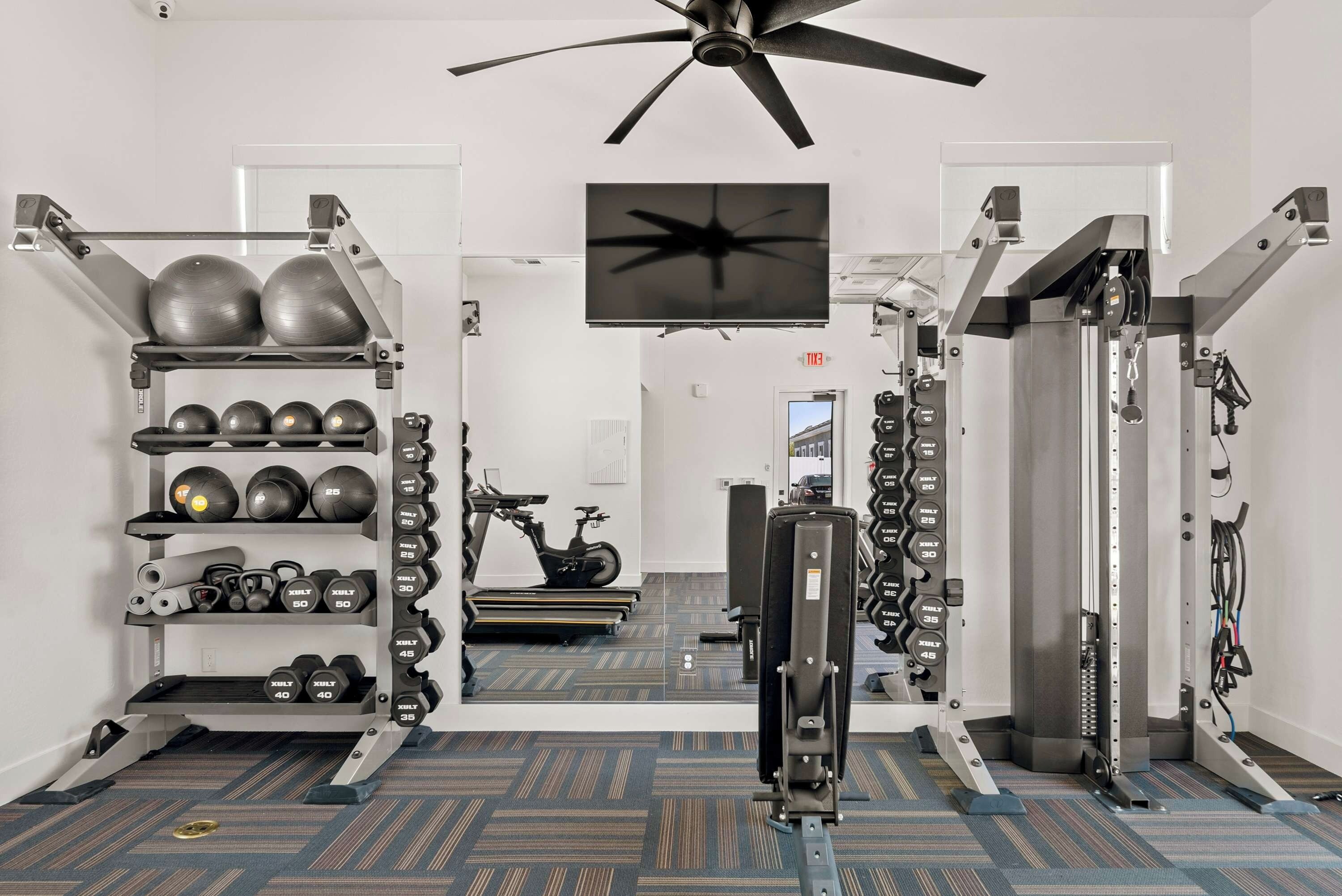 A gym with weightlifting equipment, exercise balls, and a treadmill.