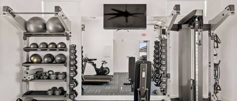 A gym with weightlifting equipment, exercise balls, and a treadmill.