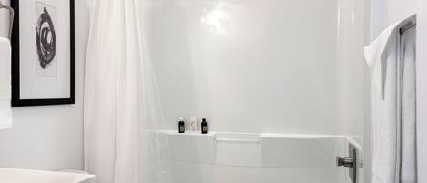 A modern bathroom with a glass-enclosed shower, a white sink, and a framed artwork on the wall.