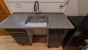 Une cuisine dotée d’un plan de travail en granit, d’appareils électroménagers en acier inoxydable et d’une poubelle noire.