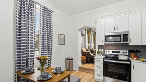 A compact kitchen with white cabinets, a microwave, an oven, and a sink. - Luxury STL Oasis: Sauna, Fire pit, Hot Tub & Games (St. Louis)