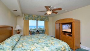 A bedroom with a bed, a ceiling fan, a TV cabinet with a beach view, and a window with curtains. - Terrific hotel suites in Fort Lauderdale with fitness room and AC (Fort Lauderdale)