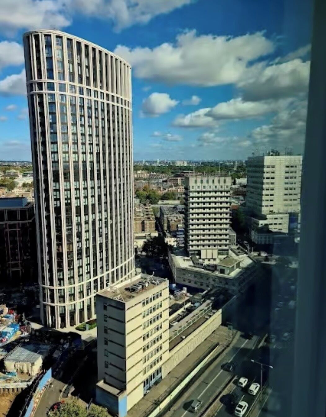 A high-rise building with a curved facade, surrounded by other buildings and a clear sky.