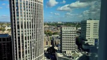 A high-rise building with a curved facade, surrounded by other buildings and a clear sky.
