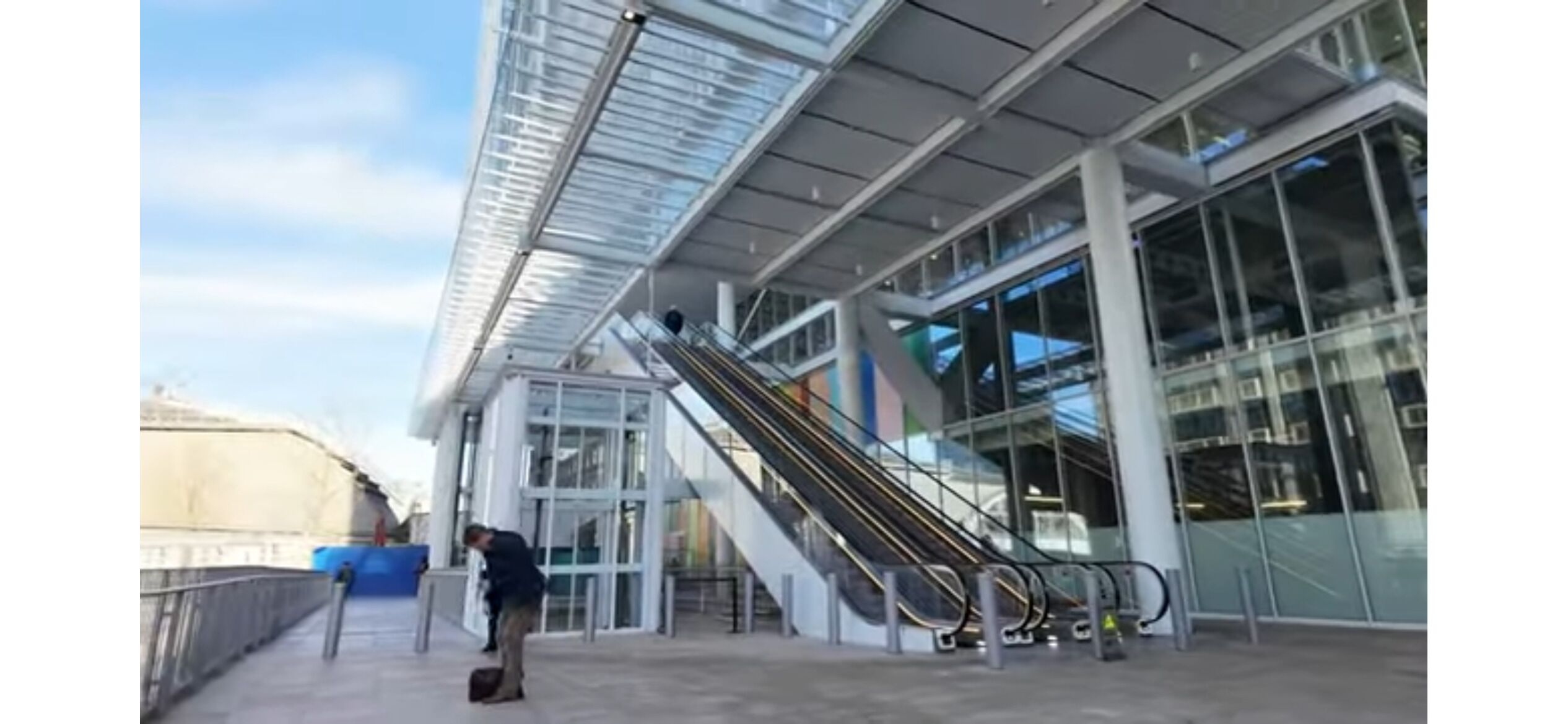 A modern building with a glass facade, a staircase, and an escalator.
