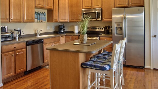 A kitchen with wooden cabinets, a stainless steel refrigerator, a microwave, a stove, and a coffee maker. - Steps to the pool 10 min to Bethany Beach, Water Views Kayaks & Free Activities Inc Golf @ Bear Trap (Millville)