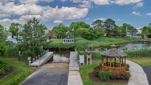 A gazebo near a pond with a wooden dock, surrounded by greenery and houses. - Steps to the pool 10 min to Bethany Beach, Water Views Kayaks & Free Activities Inc Golf @ Bear Trap (Millville)