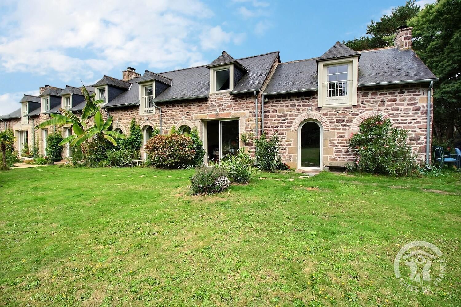 Une rangée de maisons en pierre, avec une pelouse et un jardin bien entretenus.
