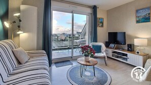 Un salon moderne avec un canapé, un téléviseur et une table basse.