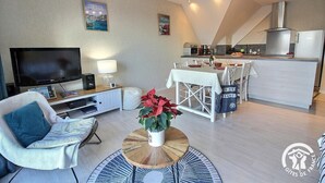 Un salon moderne doté d’un téléviseur à écran plat, d’un canapé, d’une table basse et d’un coin repas avec une table et des chaises.