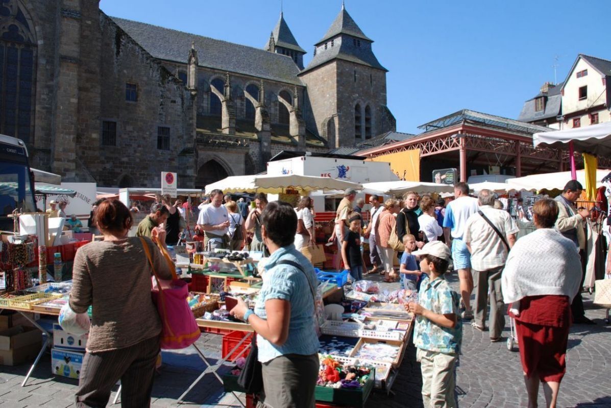 Un mercado al aire libre concurrido, con puestos variados y gente comprando.