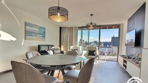 Un'elegante zona pranzo con un tavolo rotondo e sedie, ampie finestre con vista e un lampadario.