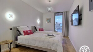 Una camera da letto moderna con due letti, un piccolo tavolo rotondo e una TV a parete.