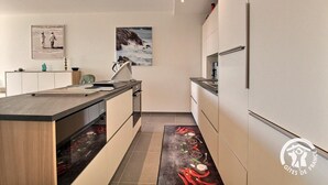 Una cucina moderna con isola centrale, mobili bianchi e schienale in piastrelle.