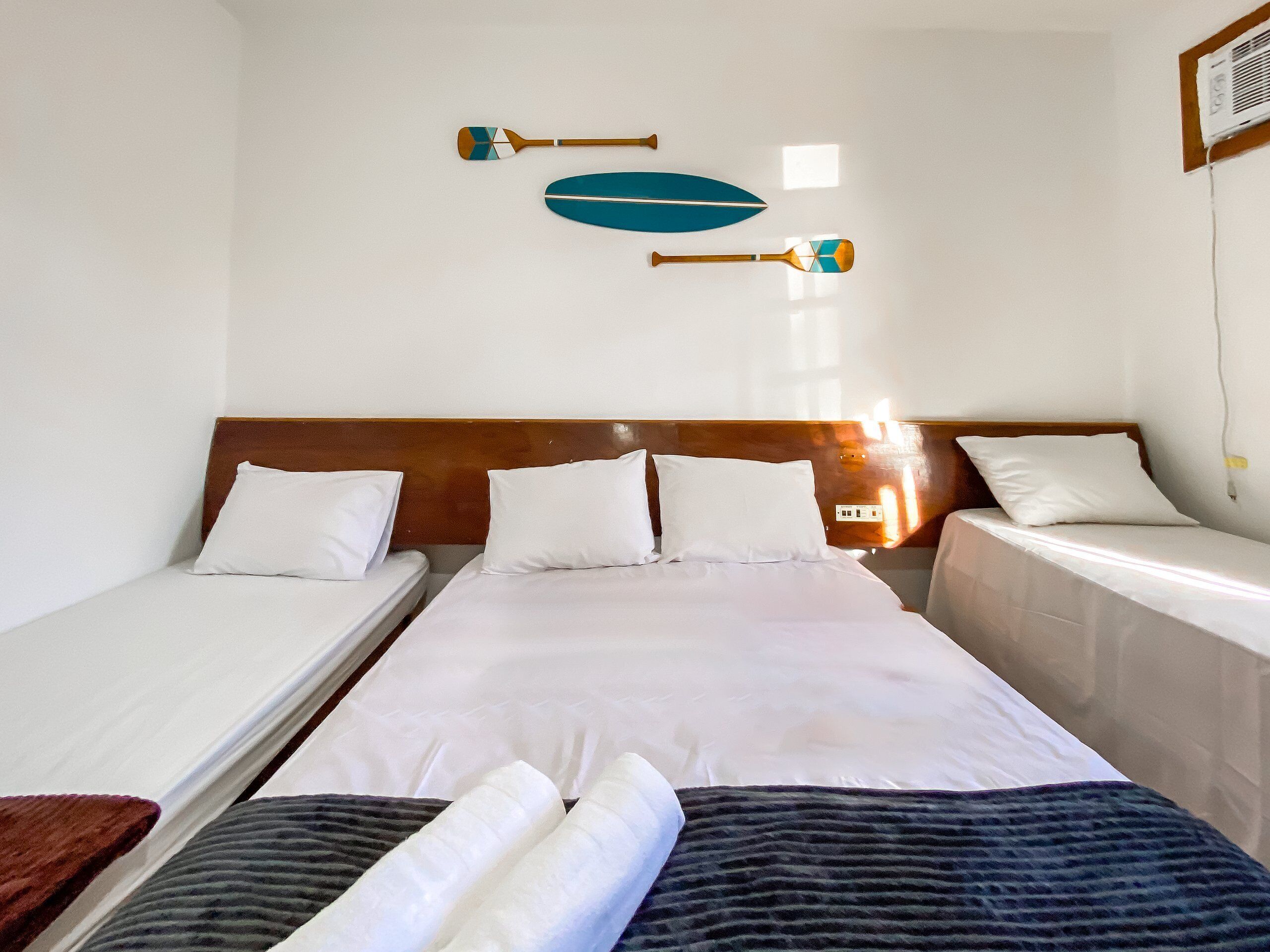 Ein Hotelzimmer mit einem Einzelbett, zwei Kissen, einem Holz-Kopfende und zwei Wandpaneelen.