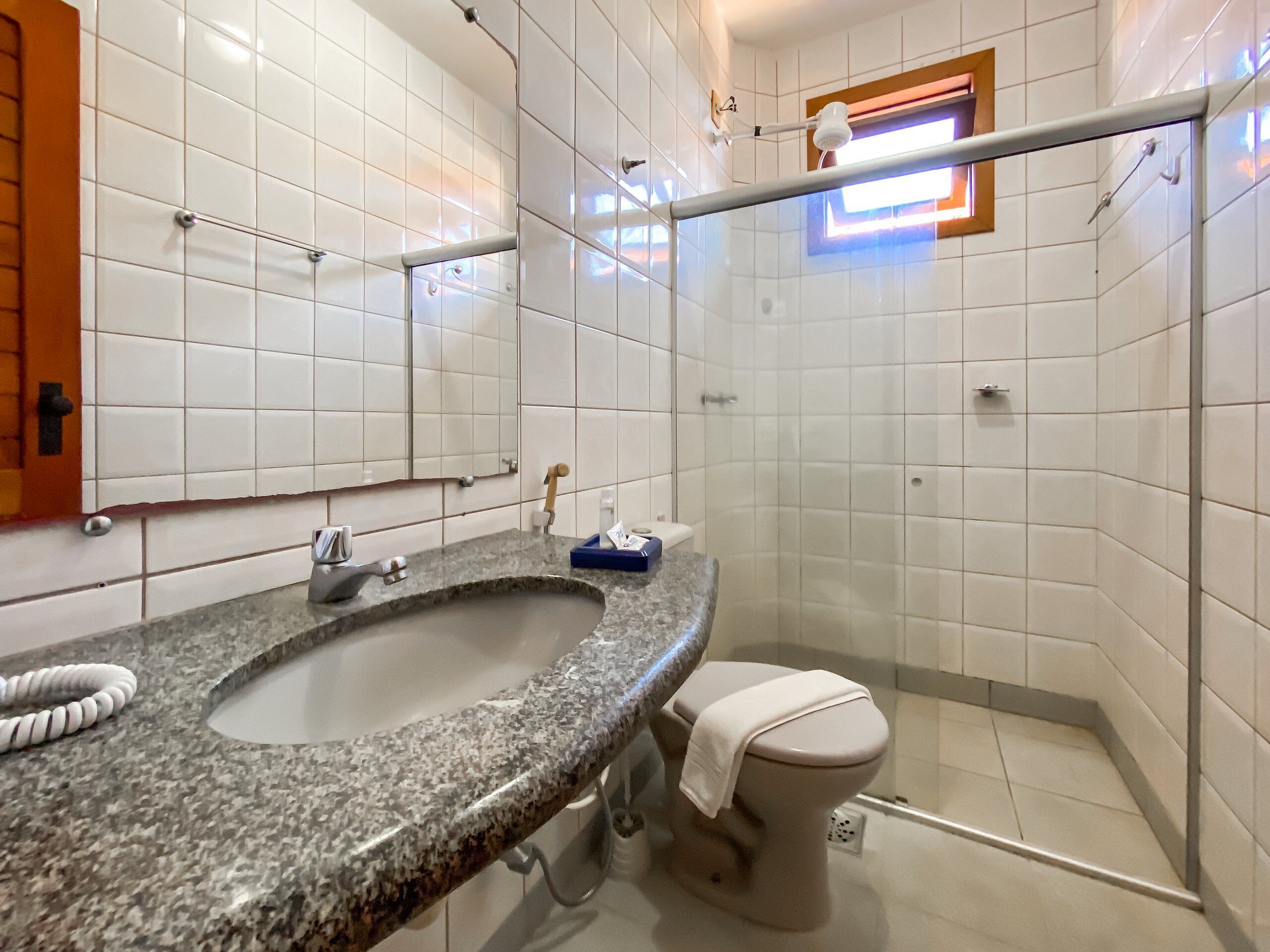 A bathroom with a granite sink, a toilet, and a glass shower enclosure.
