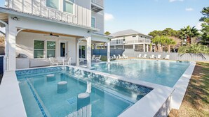Ein moderner Poolbereich mit überdachter Terrasse und Liegestühlen.