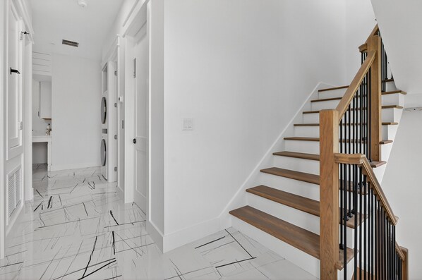 A modern interior with a wooden staircase and white walls. - The Grand 30A - Luxury Home in 30A Suitable for Beach Retreats & Large Groups (Santa Rosa Beach)