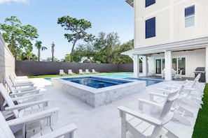 A swimming pool with lounge chairs, a covered patio area, and a building with windows and a door. - Seaside Reunion  - Luxury Home in 30A Perfect for Beach Retreats & Large Groups (Santa Rosa Beach)
