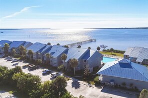 A coastal hotel with multiple blue-roofed buildings, a swimming pool, and a pier extending into the water. - Port Charlotte Private Waterfront Condo - Charlotte Harbor Water Views (Port Charlotte)