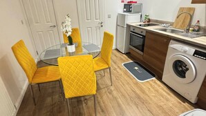 Une cuisine compacte comprenant une table à manger, des chaises, un four à micro-ondes, un lave-linge et un réfrigérateur.
