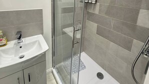 Une salle de bain moderne avec une douche à parois de verre, un lavabo blanc et un miroir.