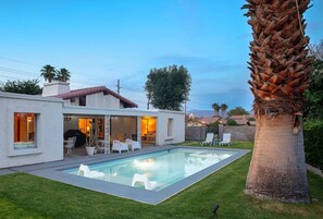 A modern house with a swimming pool, outdoor seating, and a large palm tree. - The Pearsall: Mid-Century, Pool, Backyard, Pets OK (Indio)